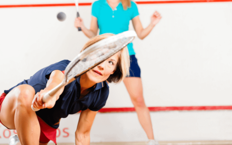 Women playing squash in a brightly lit court, with racquets and balls in motion, intense focus and determination on their faces