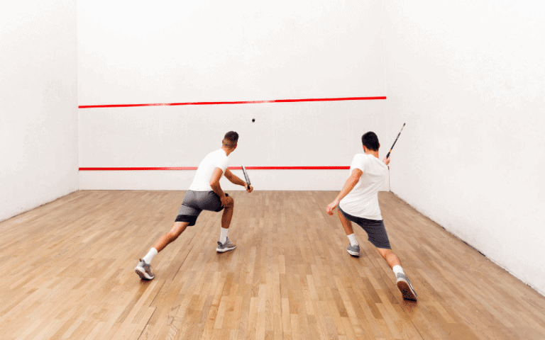 A squash player prepares to serve, eyeing the opponent across the court. The tension is palpable as they strategize their next move