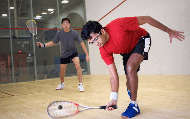 Two players on a squash court, following advanced game concepts and rules for beginners