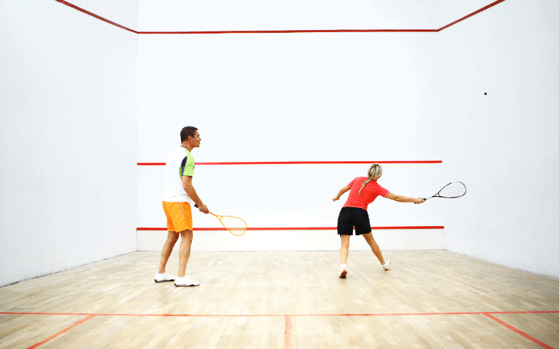 A squash player hitting the ball against the wall, focusing on footwork and racket technique to improve their game